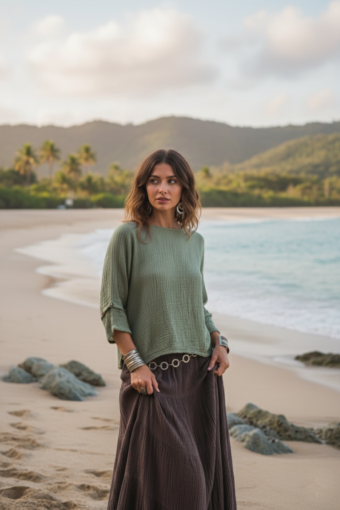 Woman standing on a beach with ocean and mountains in the background