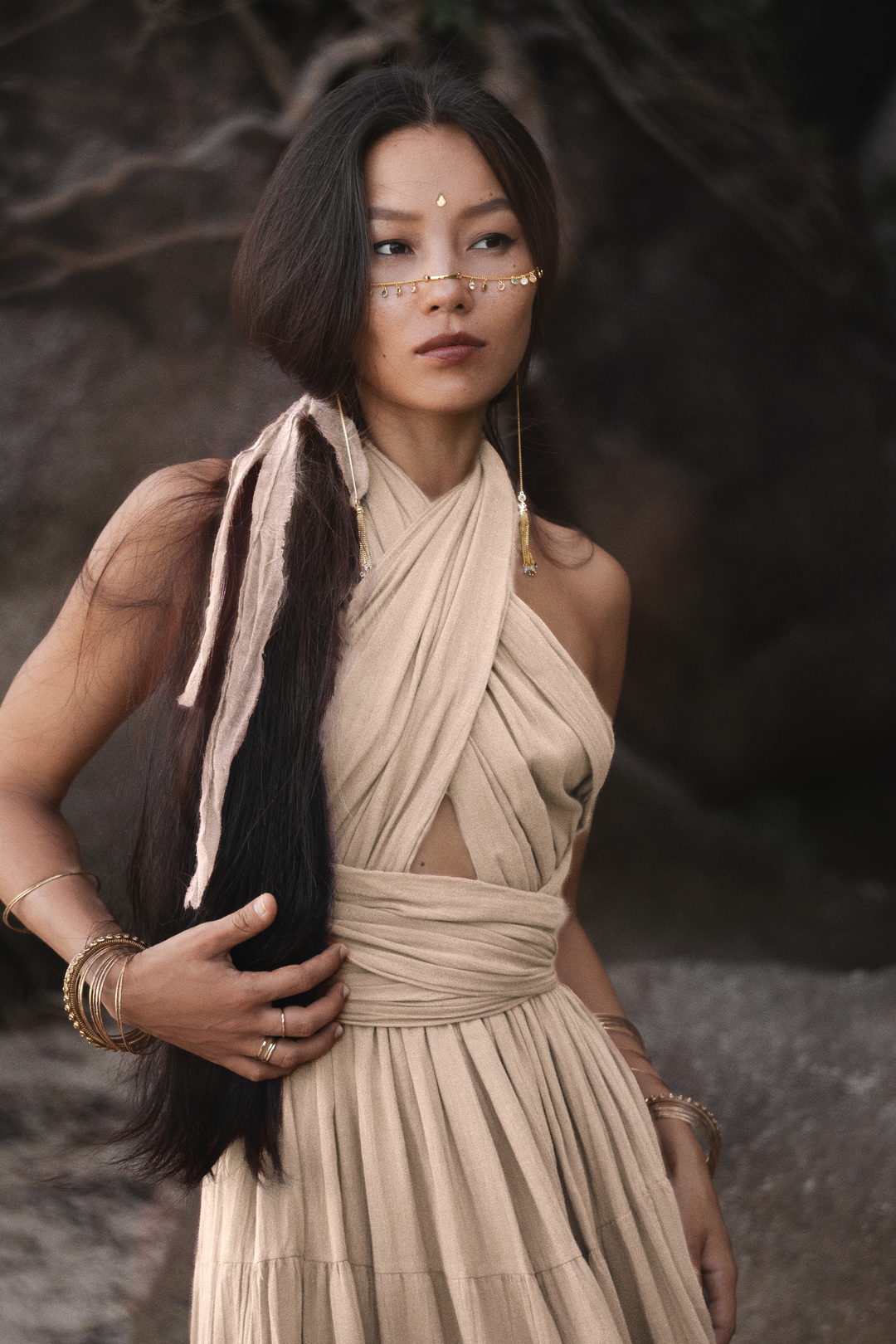 Woman in a beige dress with long dark hair against a dark background