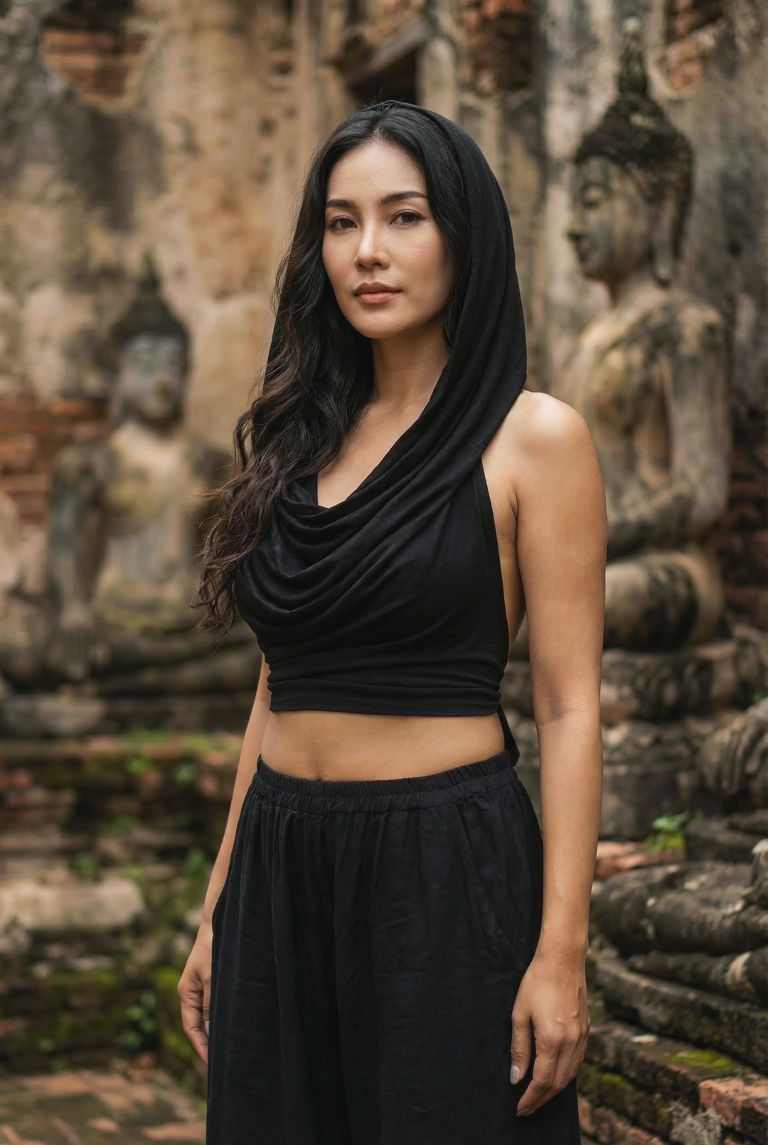 Woman in a black outfit standing in front of stone statues