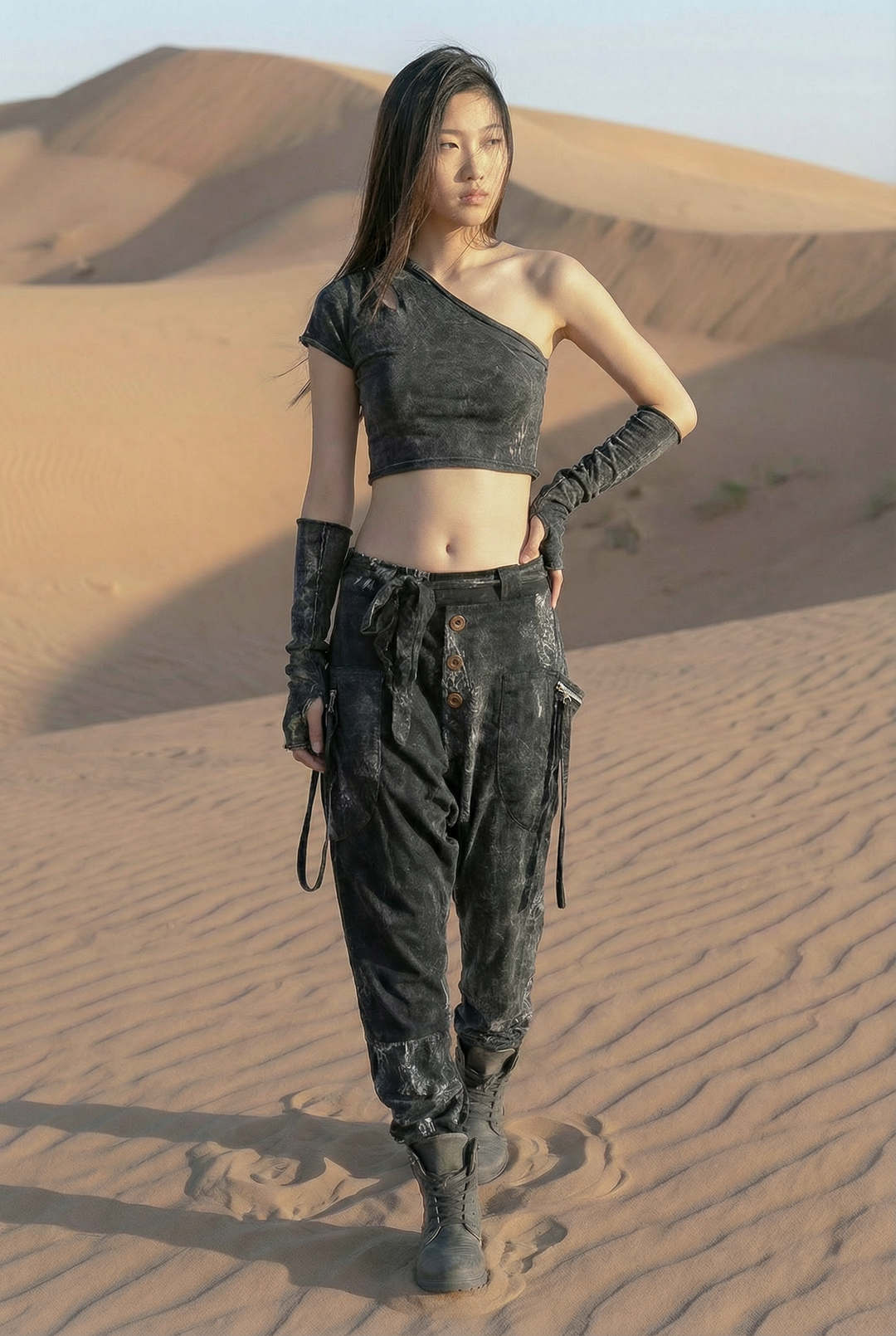 Person in desert wearing a dark outfit with gloves and boots.