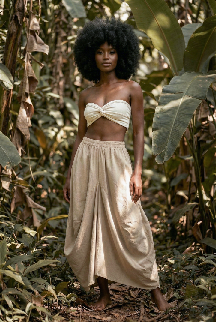 Woman in a white top and beige skirt standing in a forest setting