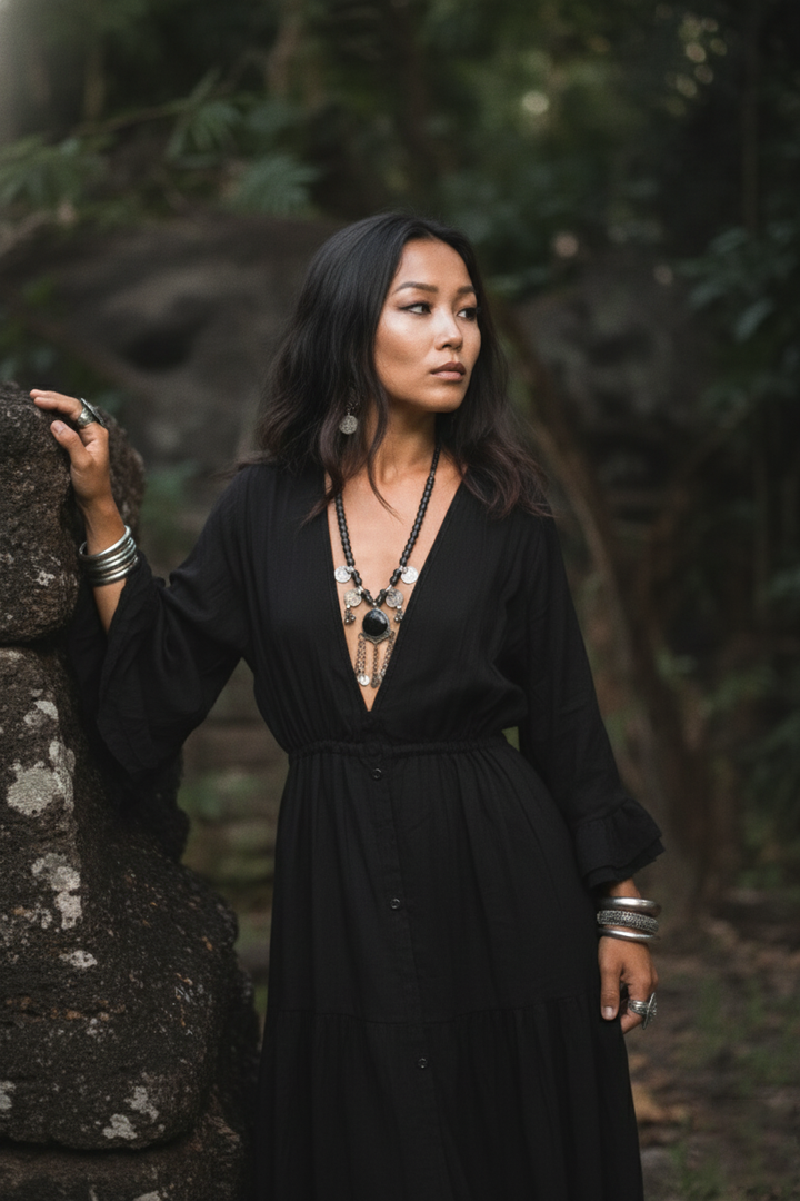 Woman in a black dress standing in a forest setting