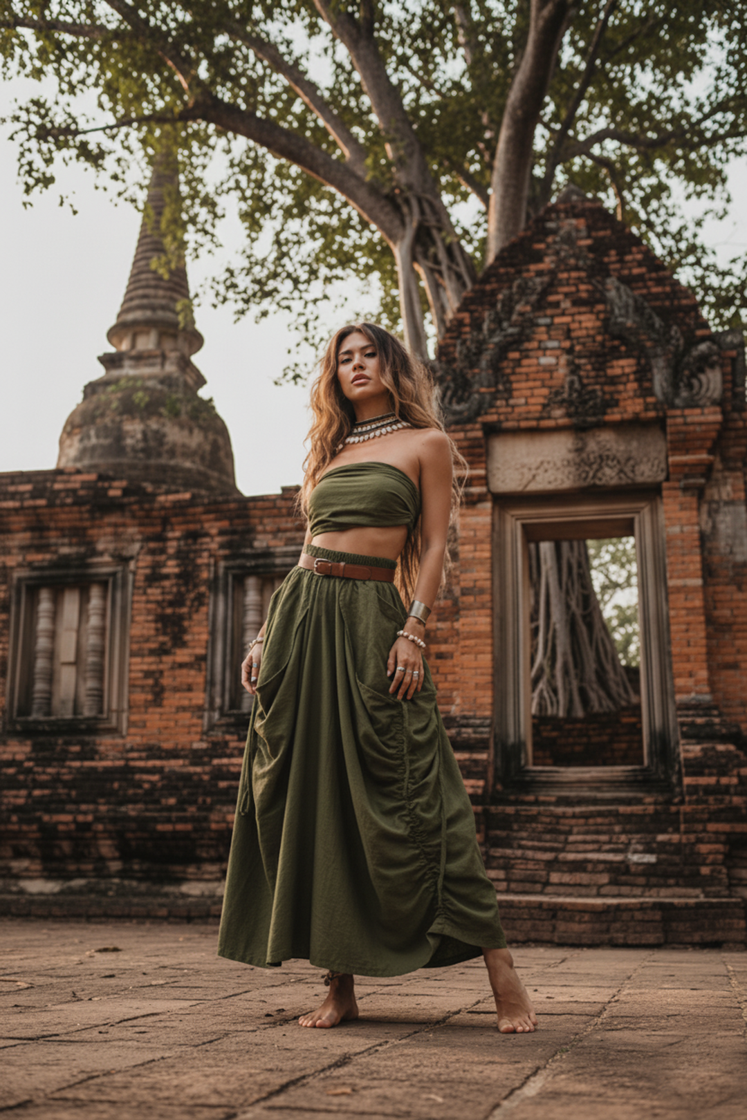 Woman in a green skirt standing in front of ancient brick temple ruins.