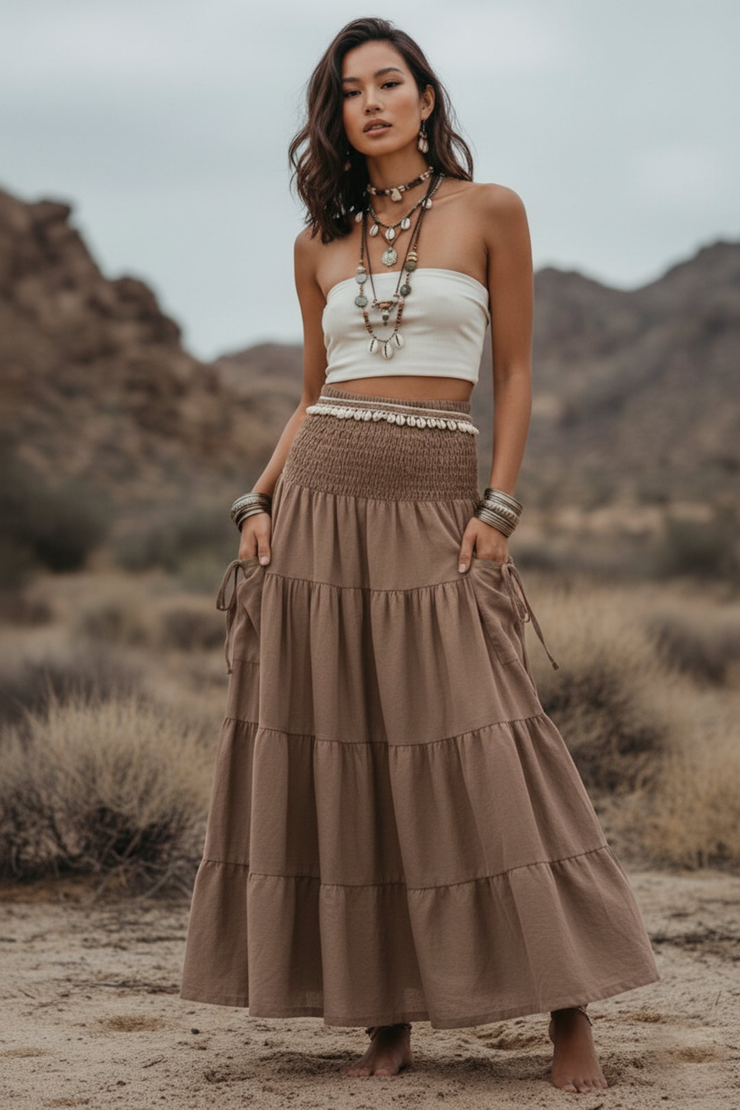 Woman in a white top and brown tiered skirt standing in a desert landscape