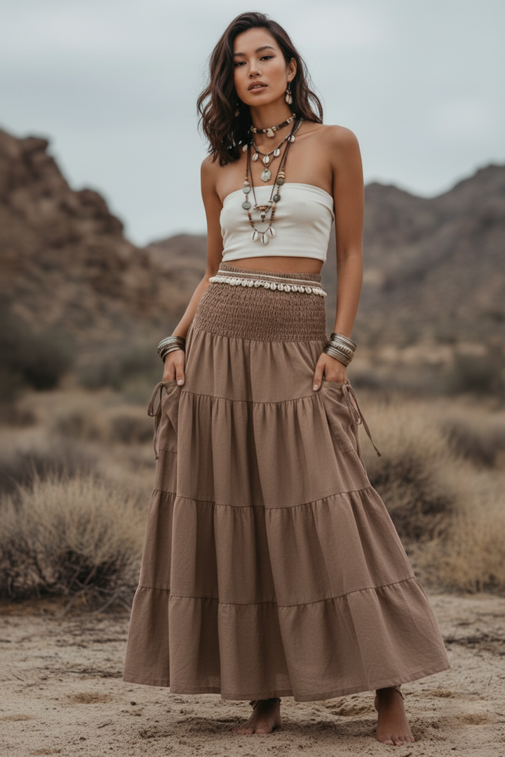 Woman in a white top and brown tiered skirt standing in a desert landscape