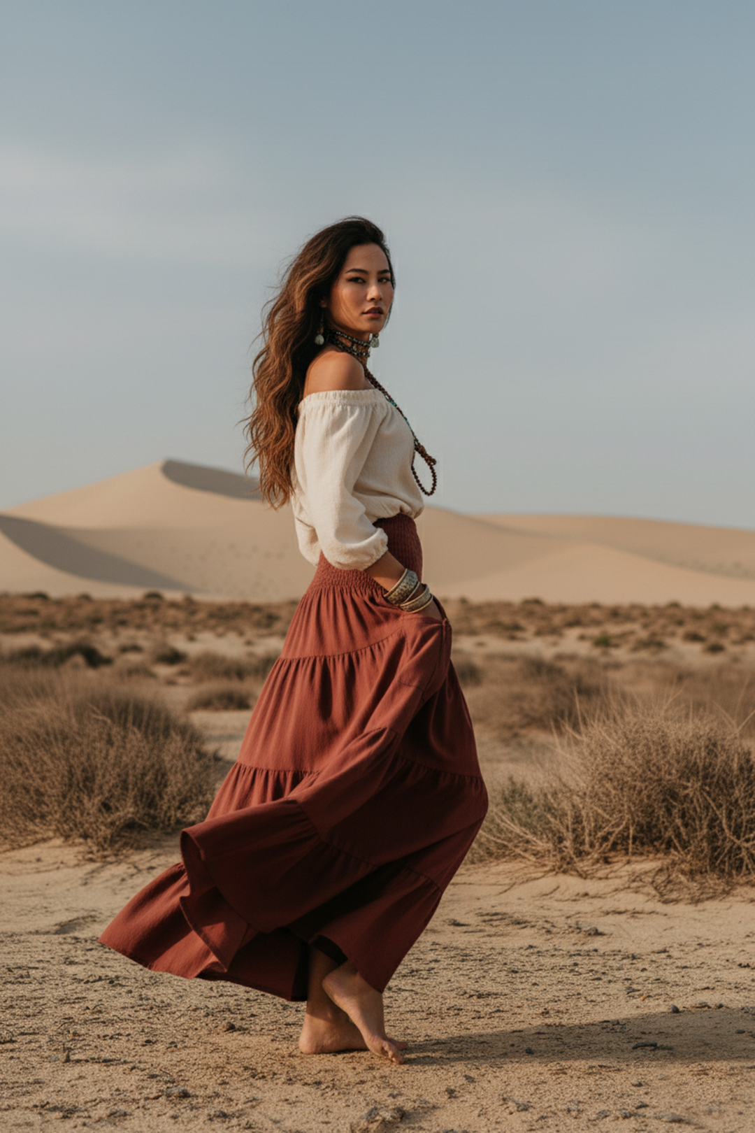 Woman in a long, flowing dress standing in a desert landscape