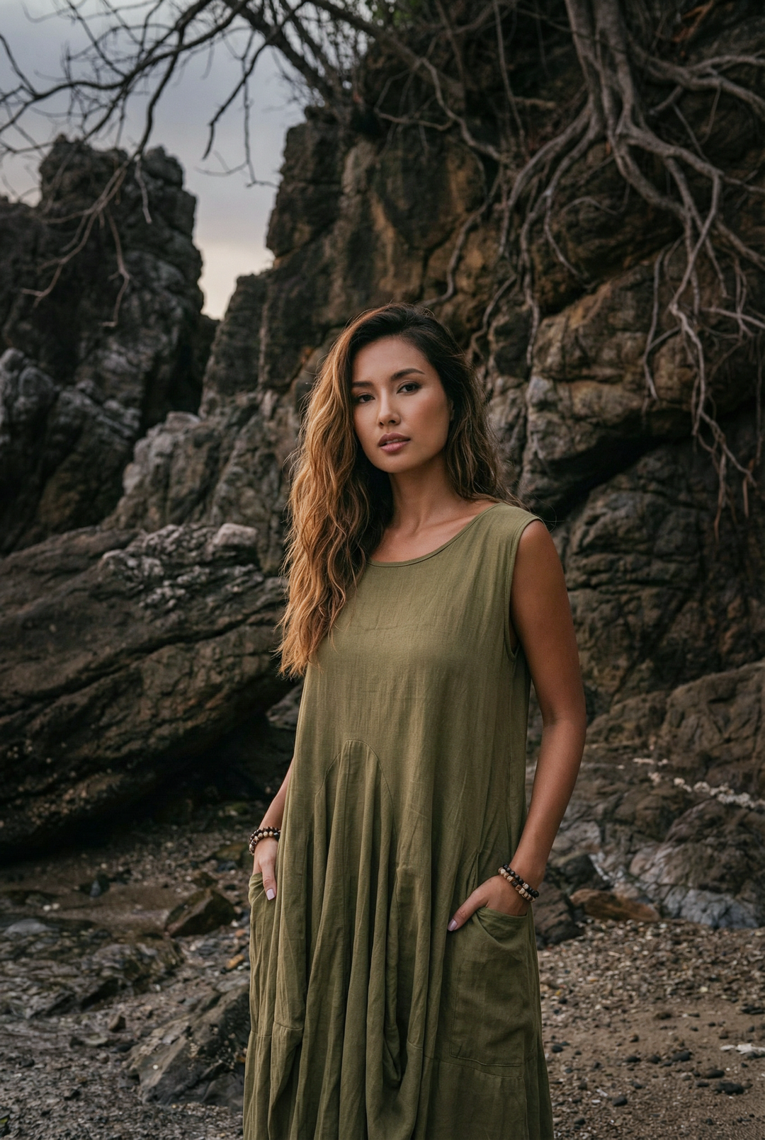 Woman in a green dress standing against a rocky background